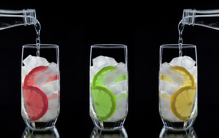 Mineral water is poured into glasses filled with ice and slices of citrus fruits. The concept of making soft drinksの写真素材
