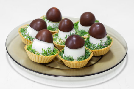 A festive snack in tartlets with salad decorated with a mushroom-shaped egg on a white wooden background. Selective focusの写真素材