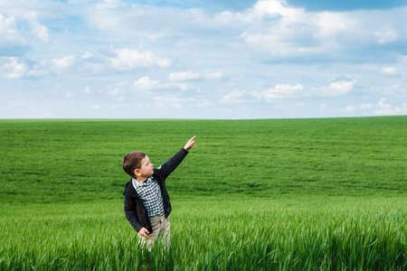 Young boy pointing with his finger to the blue sky.の写真素材