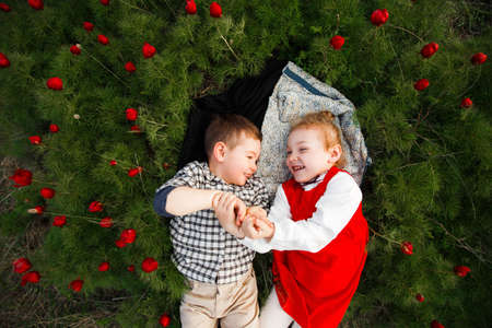 Happy children lying on green grass in spring park.の写真素材
