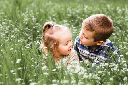 A boy and a girl are resting on the green grass in summerの写真素材