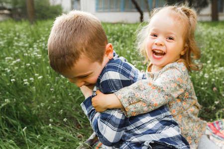 A boy and a girl are resting on the green grass in summer