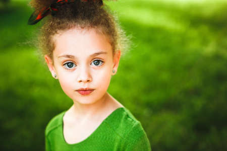 A small, curly girl in a green dress.の写真素材