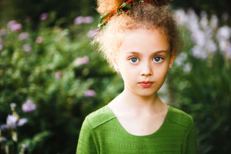 A small, curly girl in a green dress.の写真素材