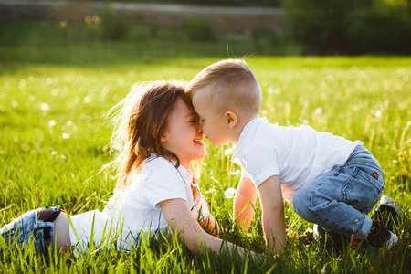 Sister and brother kiss each other lying on green grass.の写真素材
