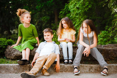 A group of children of school and preschool age are sitting in the park.の写真素材