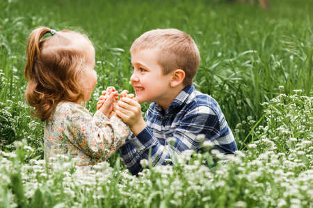 A boy and a girl are resting on the green grass in summerの写真素材
