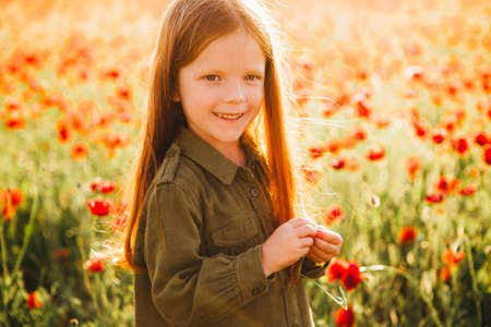 Little red-haired children are sitting in a poppy field.の写真素材