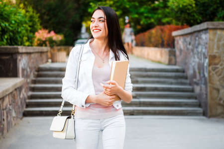 Student with notebooks and bag in front of College Universityの写真素材