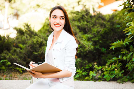 Portrait of a smiling college girl is holding book.の写真素材