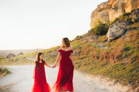 Mom and daughter in red dresses in nature.の写真素材