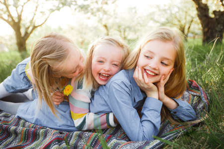 Group of happy children lying on green grass outdoors in summer parkの写真素材