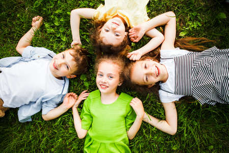 A group of kindergartners lies on the grass in the park smiling.の写真素材