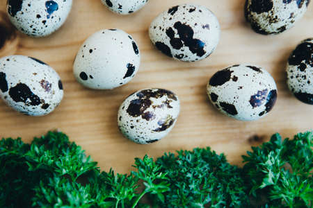 Quail eggs and greens on a wooden table. Top view.