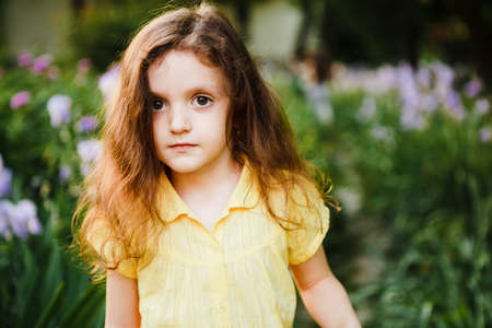 A small, curly girl in a yellow dress.の写真素材