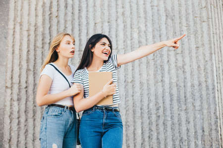Emotional girlfriends point to the distance with surprise on their faces.の写真素材