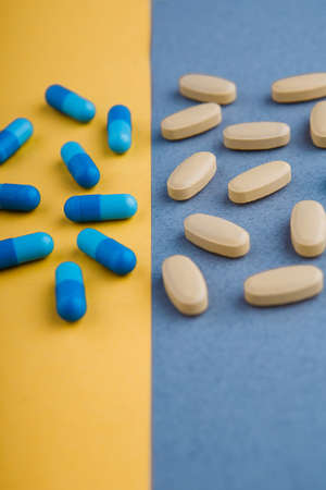 A variety of colored pills on a yellow and blue background.の写真素材