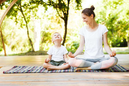 Mom and son are practicing yoga in the park.の写真素材