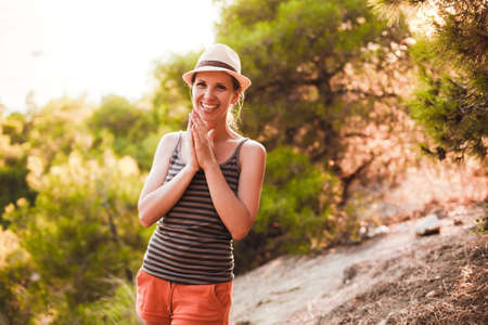 A young woman in a hat and summer clothes is walking in a pine forest.の写真素材