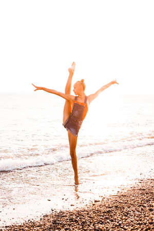 A gymnast in a beautiful pose against the background of the ocean.の写真素材