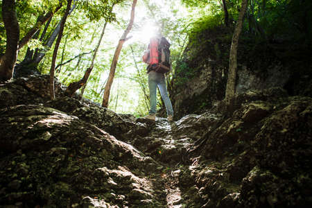 A man with a backpack and a karemate goes on a trek through the rocky gorge. Space for text.