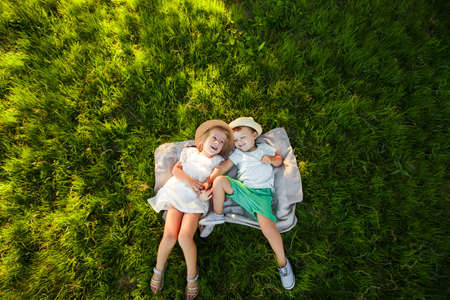 A boy and a girl are lying on the green grass. Top view. Space for text.の写真素材