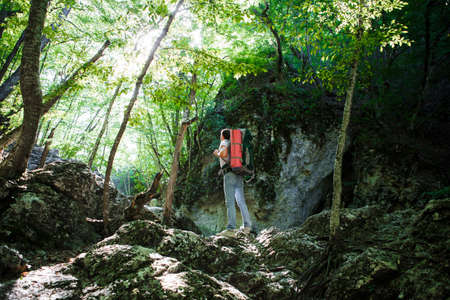 A man with a backpack and a karemate goes on a trek through the rocky gorge. Space for text.
