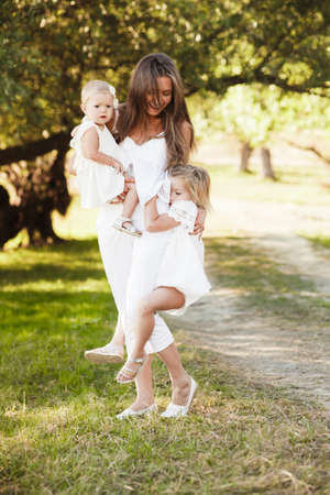 Mom with two little daughters are walking among the beautiful green forest.の写真素材