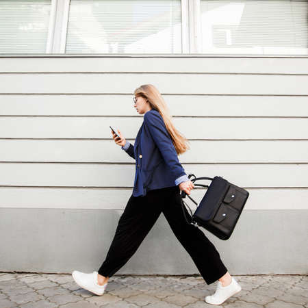 Business woman running in a suit with a briefcase along the wall.