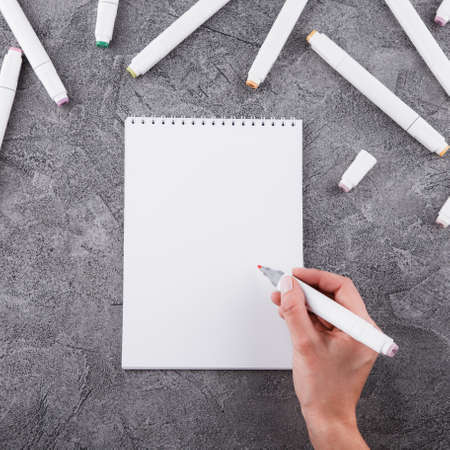 Female hands with a marker. Draw in a white notebook. Space for design. Top view.の写真素材