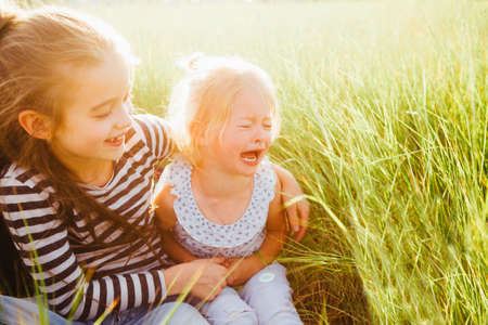 Happy smiling kids relaxing on green grass under sun, copy space. Color-toning applied.