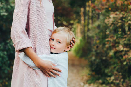 Mom and son hug and laugh in the autumn park. Space for text.