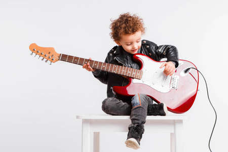 Shot of a little curls boy playing rock music with electric guitar.の写真素材