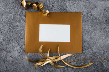 Mockup white greeting card and envelope with golden fern leaves and light background.