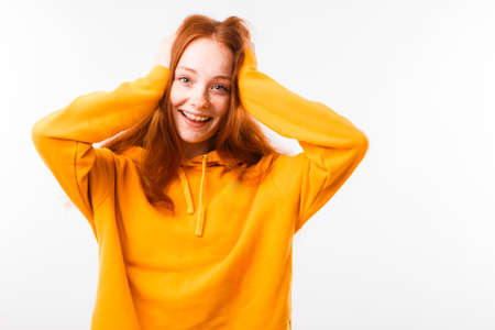Portrait of an emotional red-haired girl with freckles and braces on a white background.