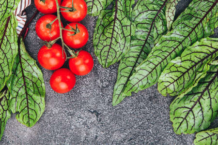 Halved Juicy Cherry Tomatoes and Basil Leaves on a black slate. Cherry tomatoes and herbs on a black slate. Concept for healthy nutrition. Top view. Copy space. Beautiful detox menu layout.の写真素材