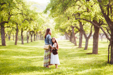 Two sisters in boho outfits are walking around the village. Beautiful, summer landscape. Country Holiday...の写真素材