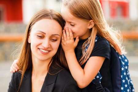 Mom leads her daughter to school. Return to school. Woman and girl with backpack behind the back....