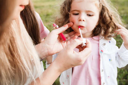 Blonde mother with two cute daughters are walking and having fun outdoors. Stylish, casual clothes.の写真素材