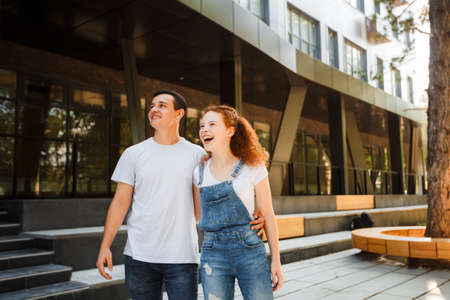 A young couple is walking in the modern city, holding hands. Inspect the conceptual archeology.の写真素材