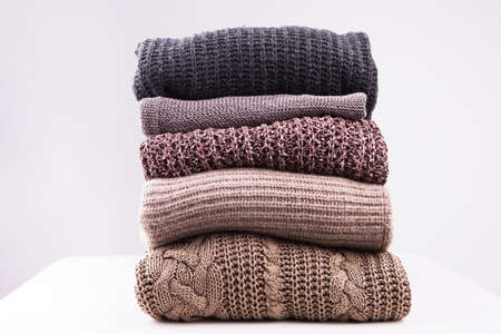 A stack of knitted winter sweaters on a white background. Beautiful texture of knitting.