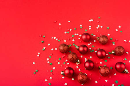 Red Christmas balls on a red background with color confettiの写真素材