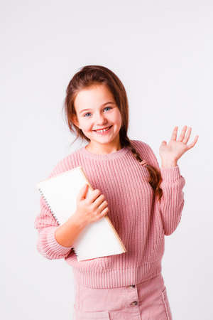 Beautiful schoolgirl with a notebook for homework on a light gray background.の写真素材