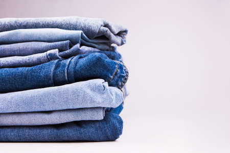 A stack of denim in different shades of blue on a white background. Blank for advertising laundry.の写真素材