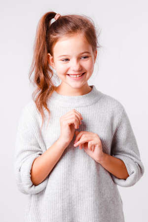 Beautiful girl of school age on a light gray background. Bright emotions.の写真素材