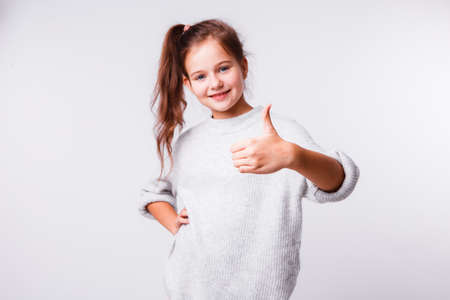 Beautiful girl of school age on a light gray background. Bright emotions.の写真素材