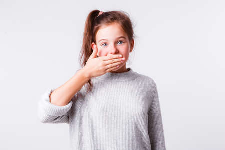 Beautiful girl of school age on a light gray background. Bright emotions.の写真素材