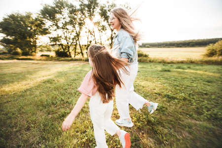 Blonde mother with two cute daughters are walking and having fun outdoors. Stylish, casual clothes.の写真素材