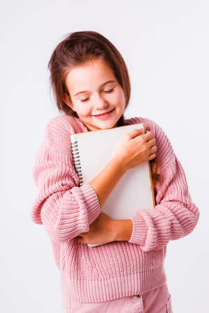 Beautiful schoolgirl with a notebook for homework on a light gray background.の写真素材