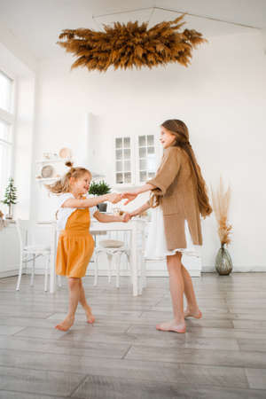 Two sisters play in a bright, stylish kitchen. Beautiful interior.の写真素材